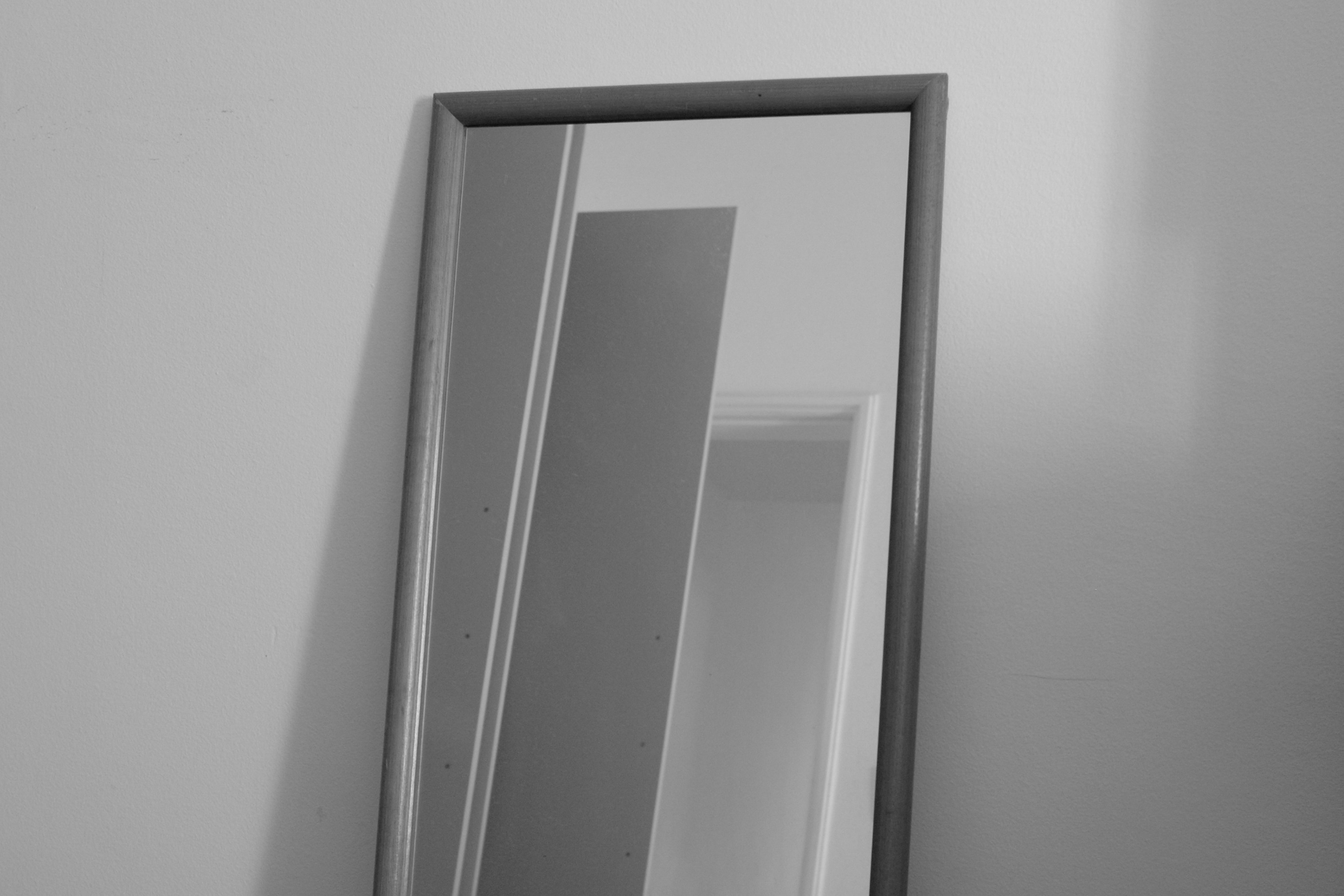 a black and white photo of a mirror on a wall